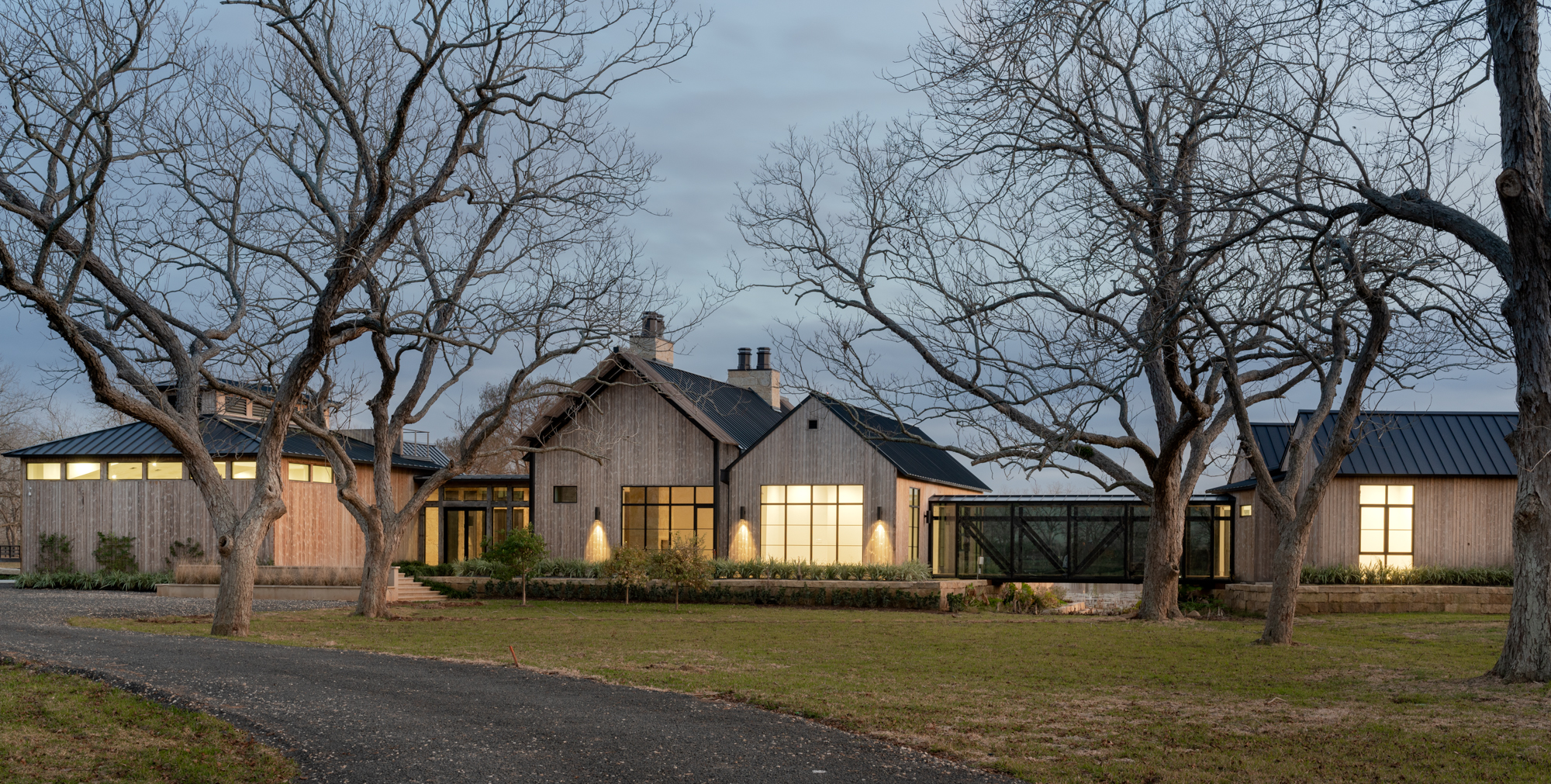Front view of the exterior of the Fulshear Modern Ranch Estate featuring Kebony Modified Wood Character Decking in Fulshear, Texas at night
