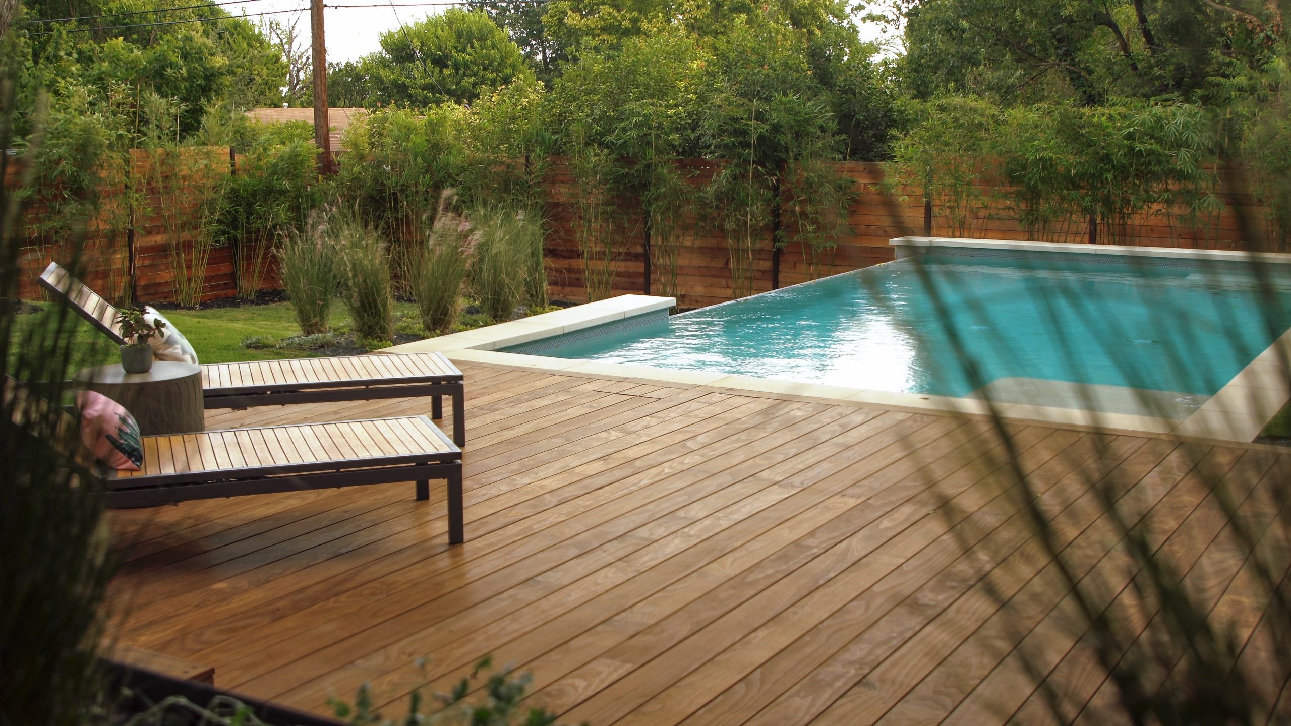 Exterior deck patio with reclining chairs next to a pool features Kebony Modified Wood Clear Cladding