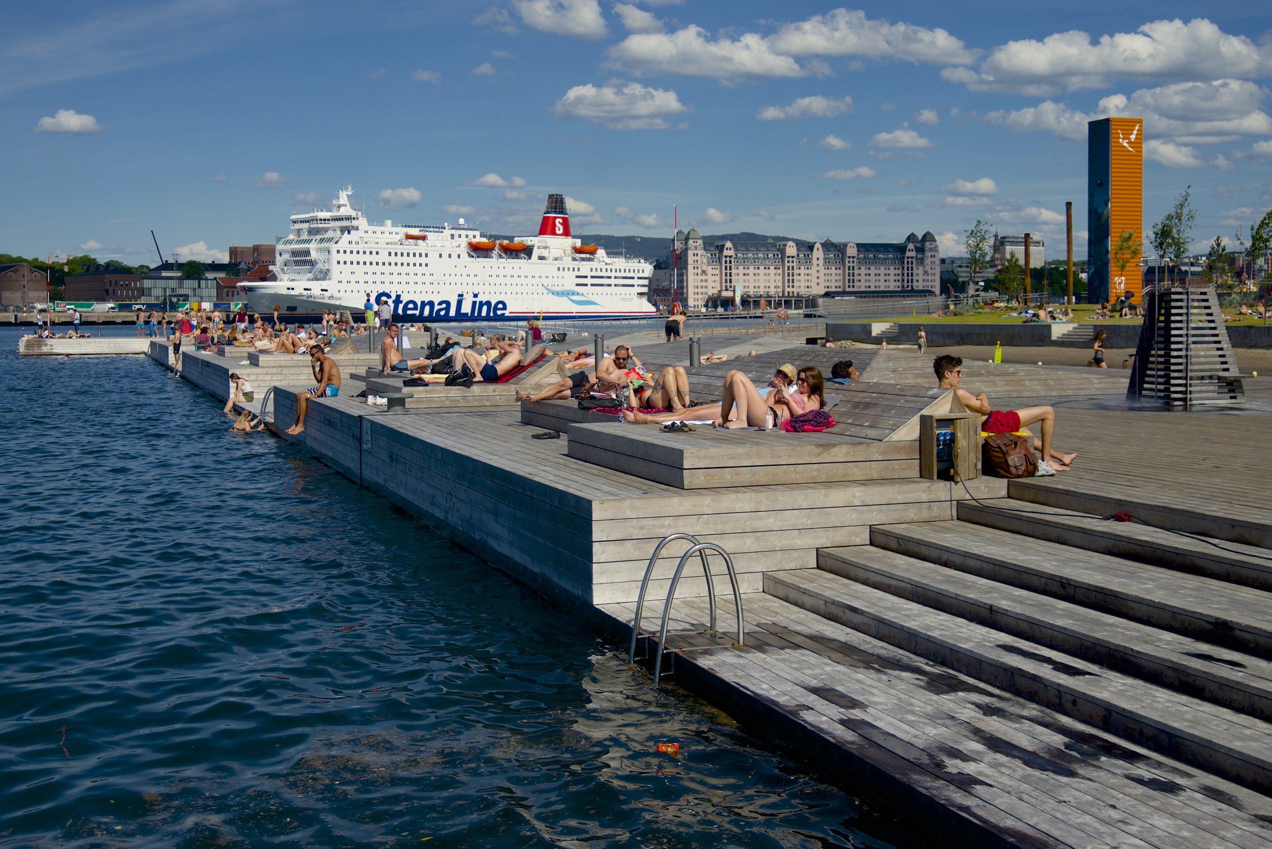 People enjoy the pool at Sørenga Harbor Pool in Oslo, Norway featuring Kebony Modified Wood Character Pier Decking with a cruise ship docked nearby in the background