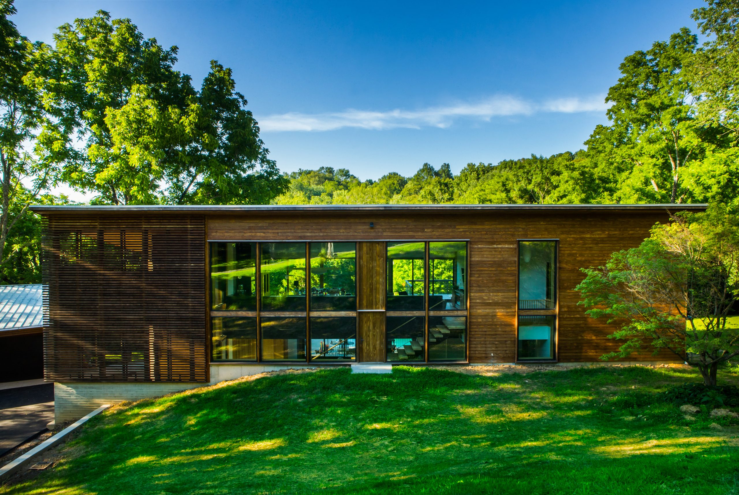 Exterior view of the front entrance with surrounding woods of the Wood Screen House in Nashville, Tennessee during a sunny day featuring Kebony Modified Wood Clear Cladding