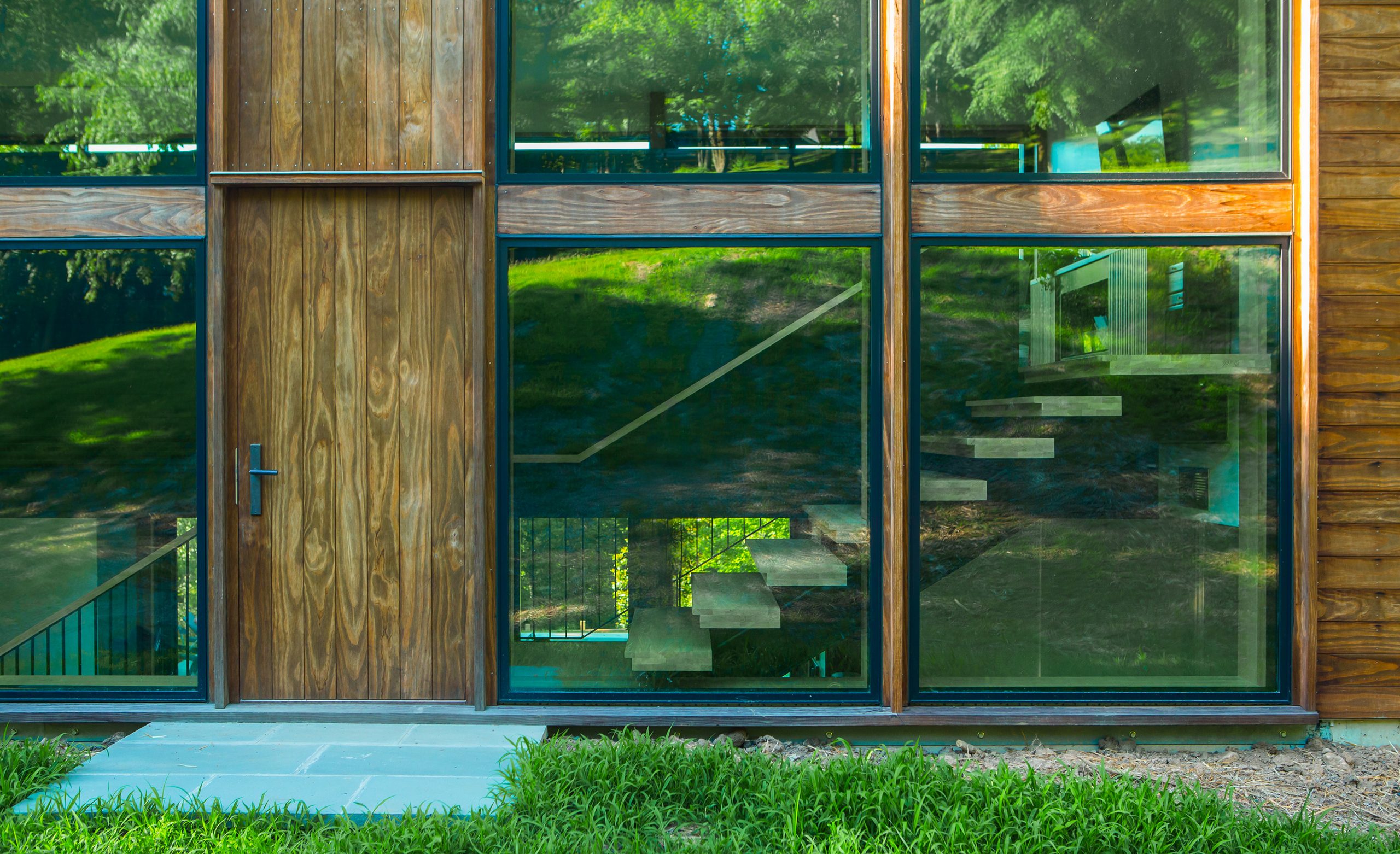 Close up view of the front entrance with surrounding woods of the Wood Screen House in Nashville, Tennessee during a sunny day featuring Kebony Modified Wood Clear Cladding