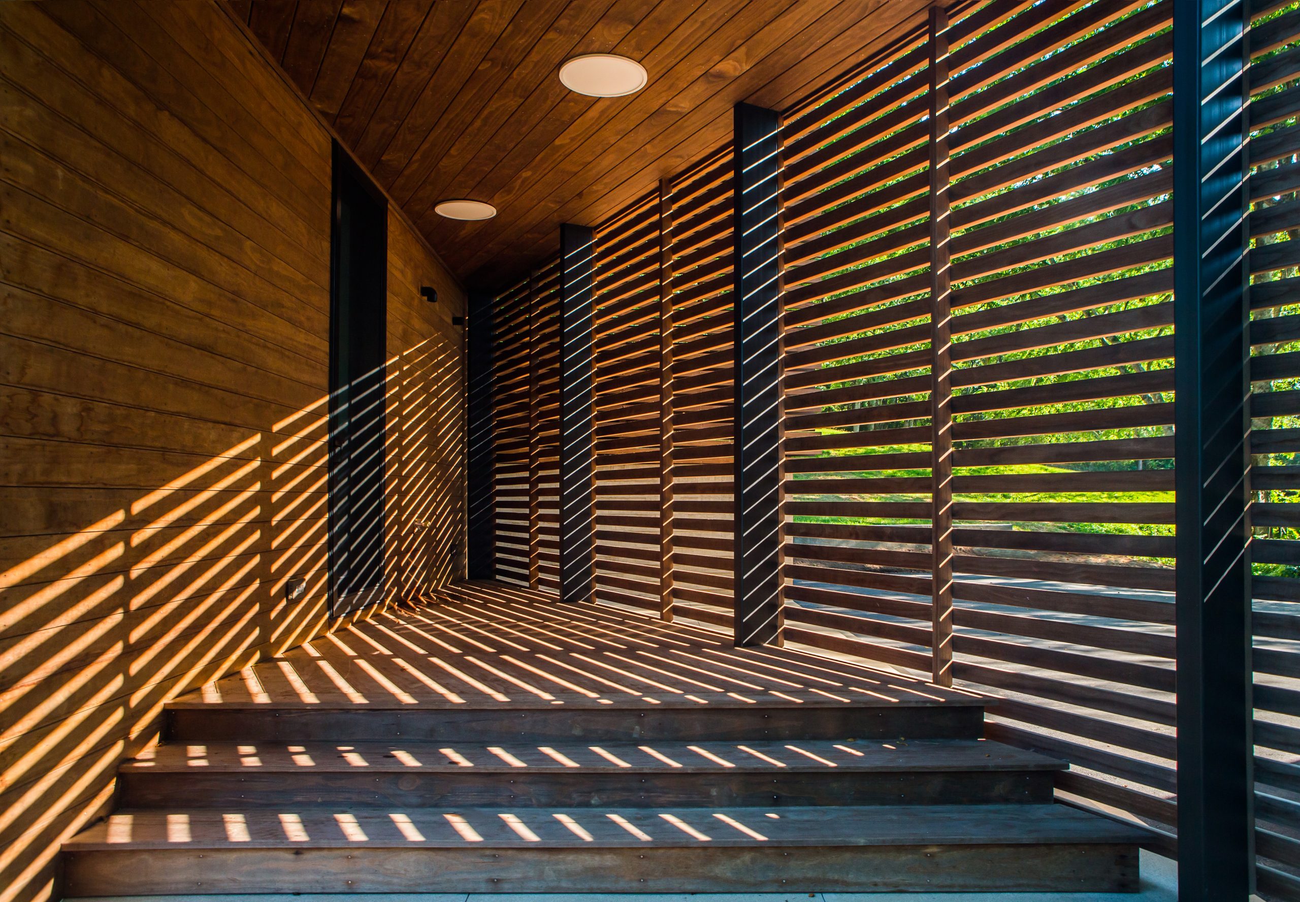 Interior view of the sun shining through the wooden slats of the Wood Screen House in Nashville, Tennessee during a sunny day featuring Kebony Modified Wood Clear Cladding