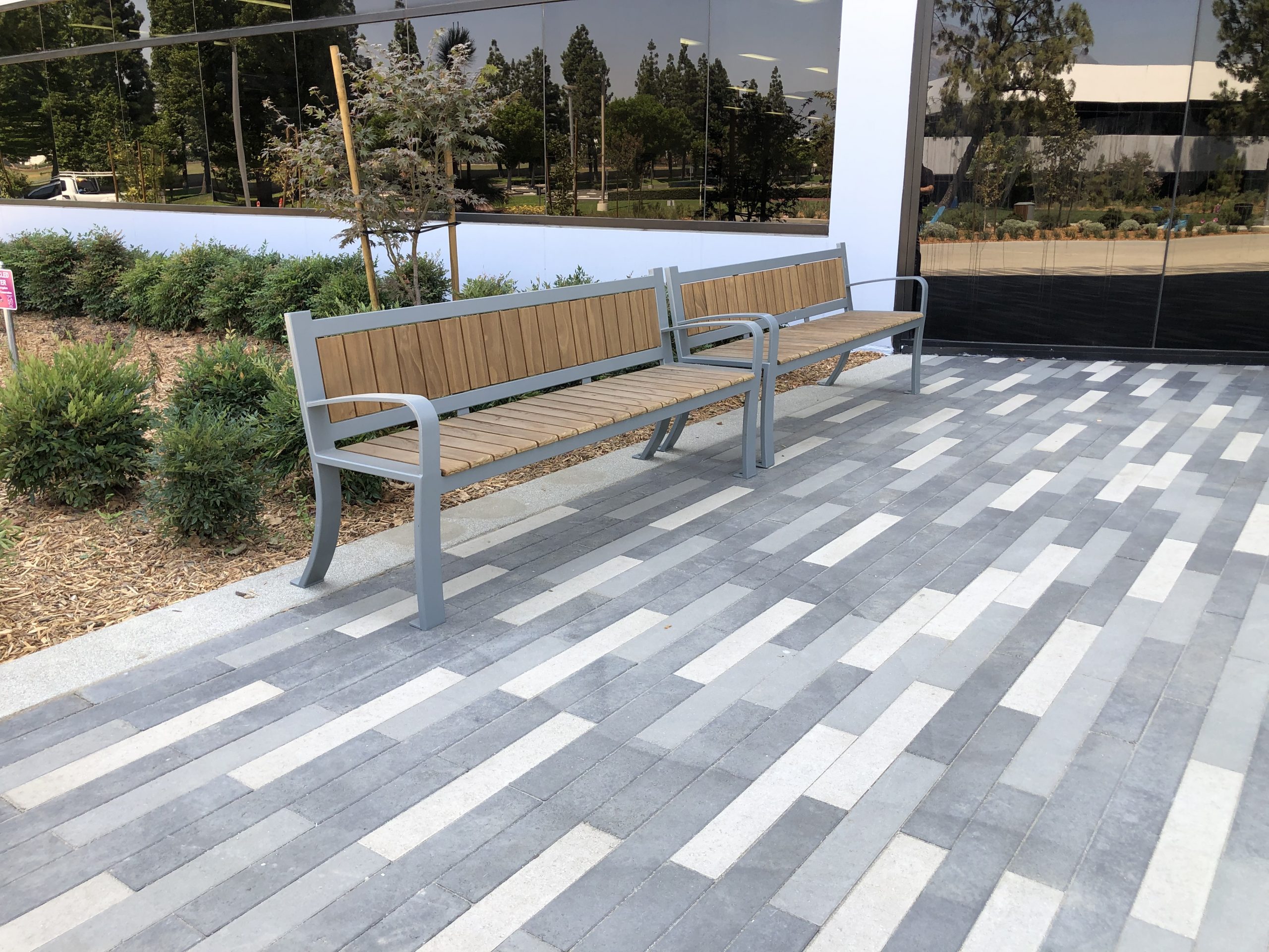 View of two bench furnishings with small bushes behind them featuring Kebony Modified Wood Clear Cladding outside the Inland Empire Health Plan in Rancho Cucamonga, California