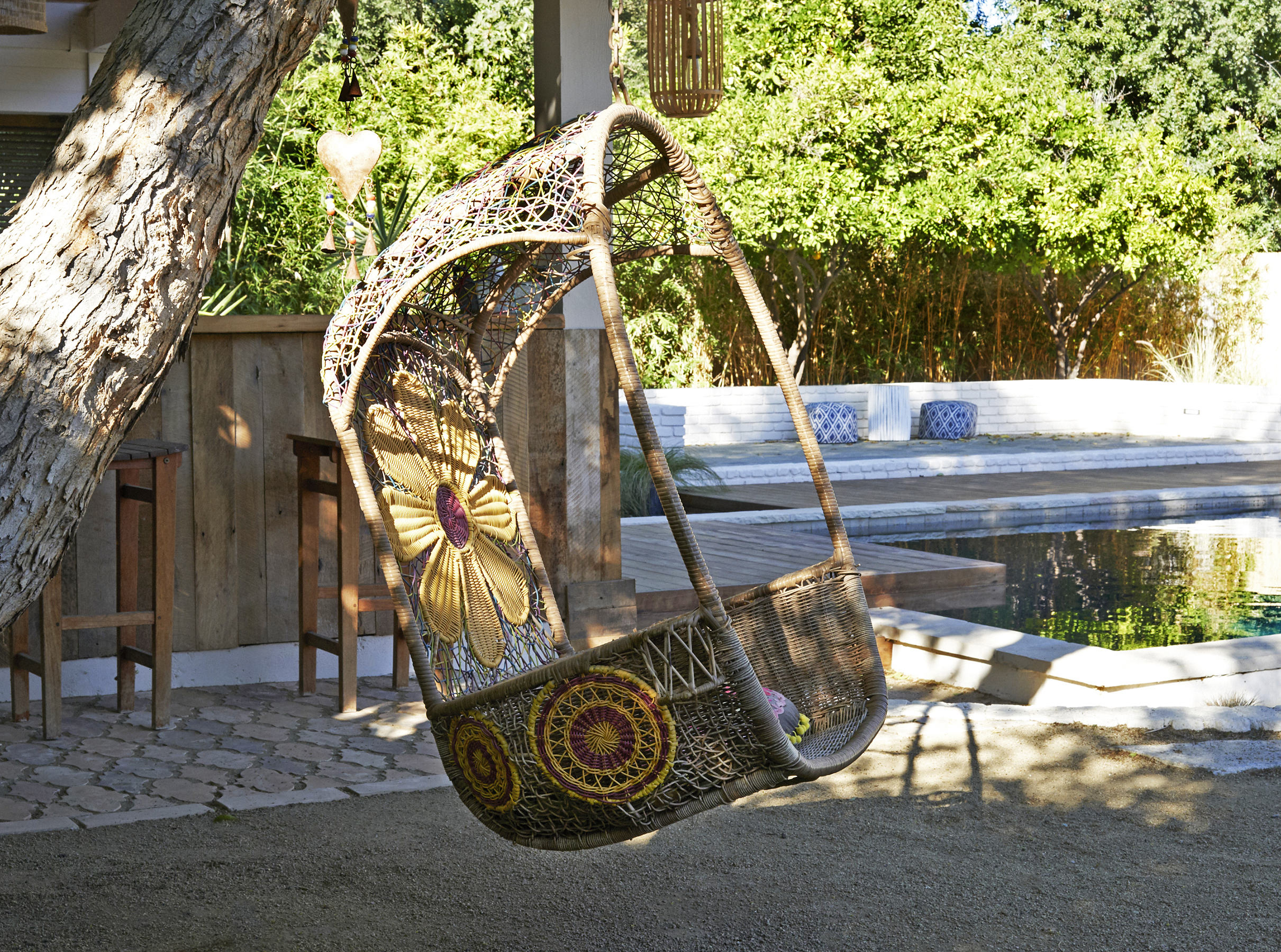 A wicker chair in the sunlight at the Rum Punch House in Los Angeles California featuring Kebony Modified Wood Clear Decking during the day by the pool house and pool