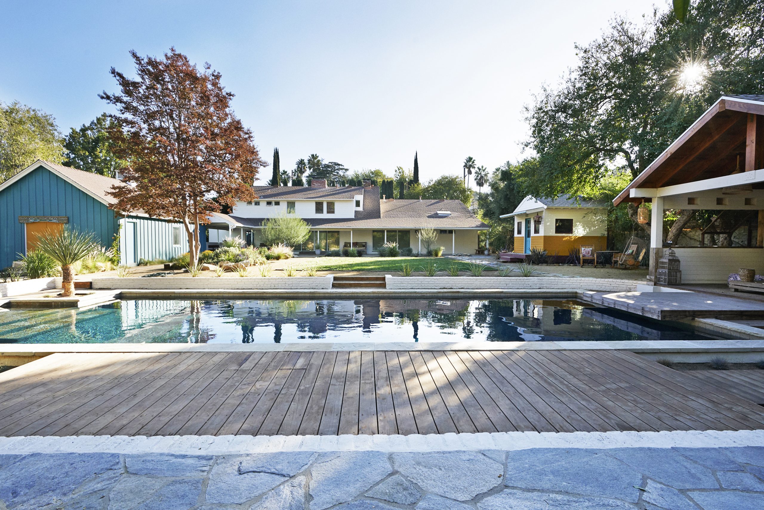 Side view of the backyard pool and pool house of the Rum Punch House in Los Angeles California featuring Kebony Modified Wood Clear Decking during the late afternoon hours.