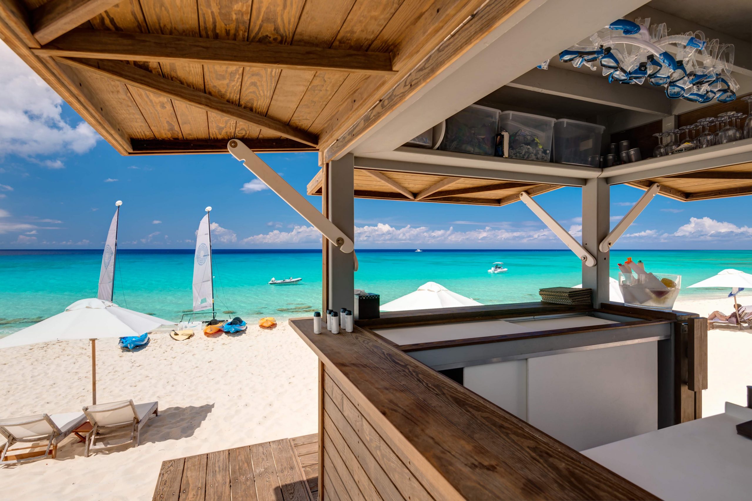 Under the awning of the Amanyara Resort Beach Hut in Turks & Caicos featuring Kebony Modified Wood Clear Cladding during the day and overlooking the beautiful blue ocean and pristine beach in the background