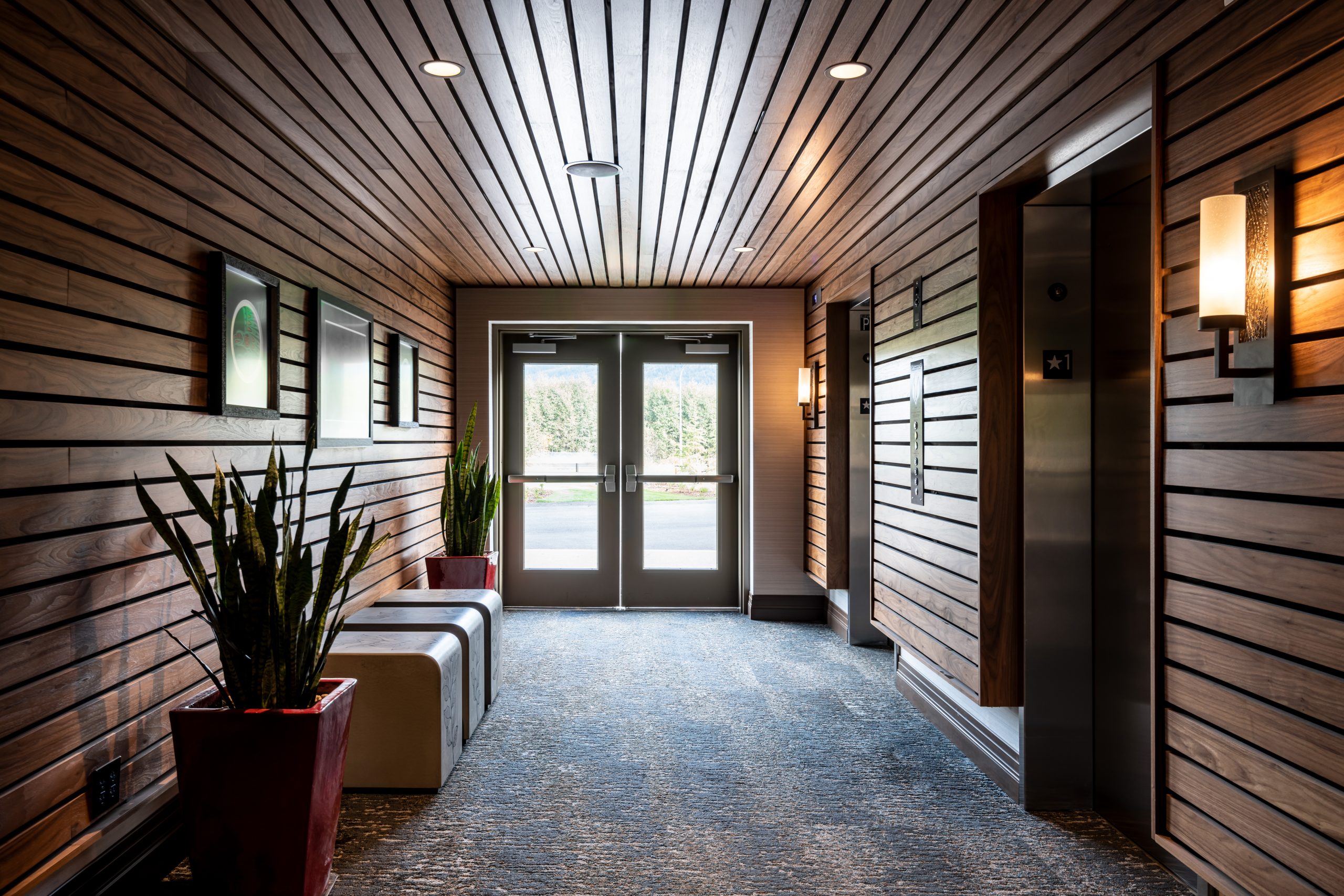 View of the elevator access in the 7 Cedars Resort Hotel Casino in Sequim, Washington featuring Kebony modified wood Clear and Character Cladding facing an exit during the day