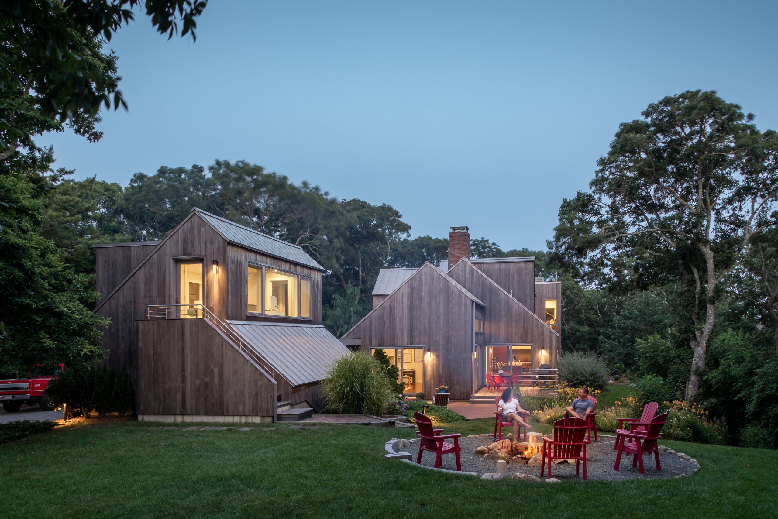 Morris Island Residence couple enjoying their backyard firepit on a beautiful evening on Morris Island in Chatham, Massachusetts featuring Kebony Modified Wood Clear Cladding