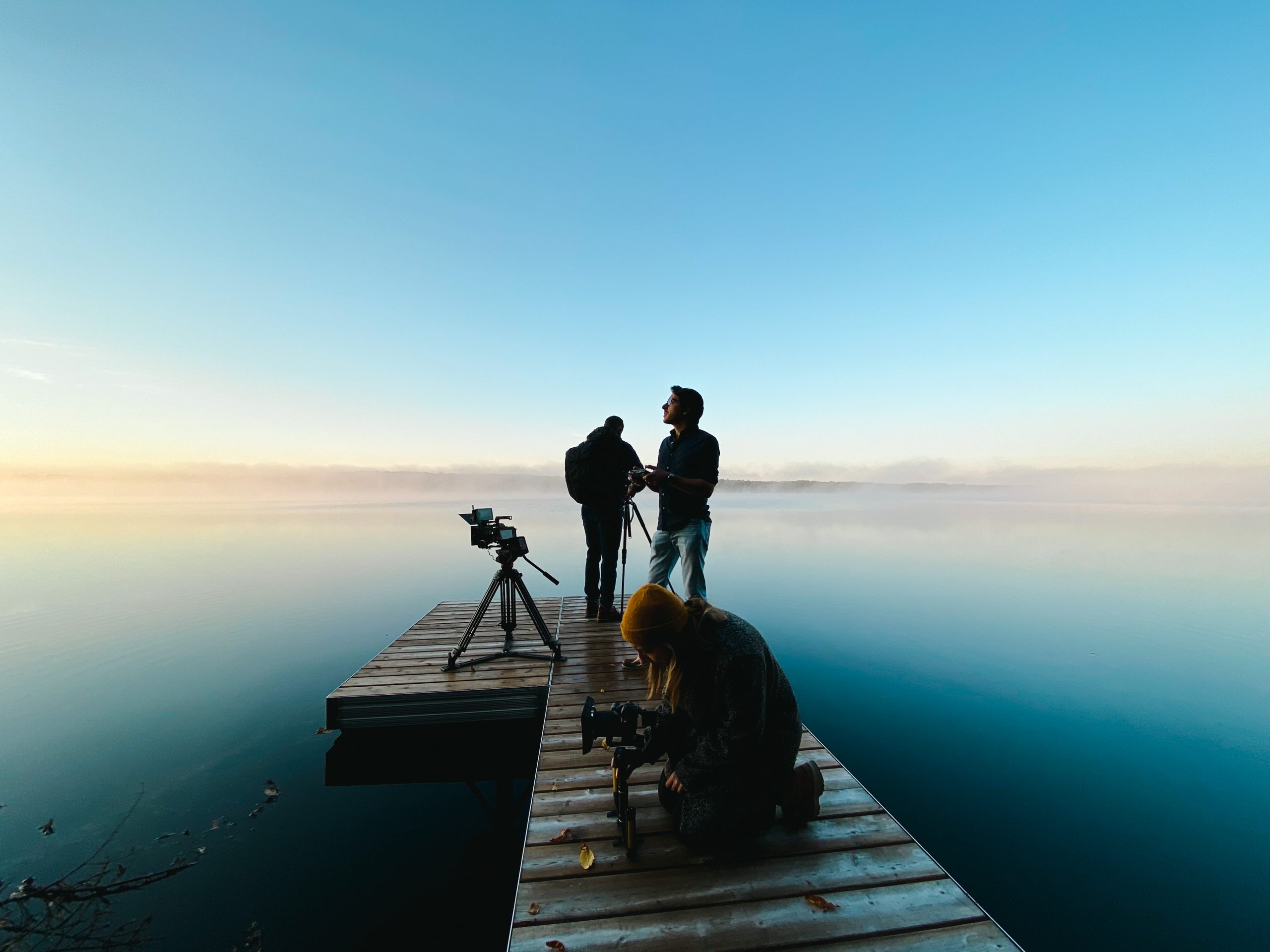 James Burniston and team looking standing on a pier that features kebony modified wood looking out over beautiful clear waters during a sunset