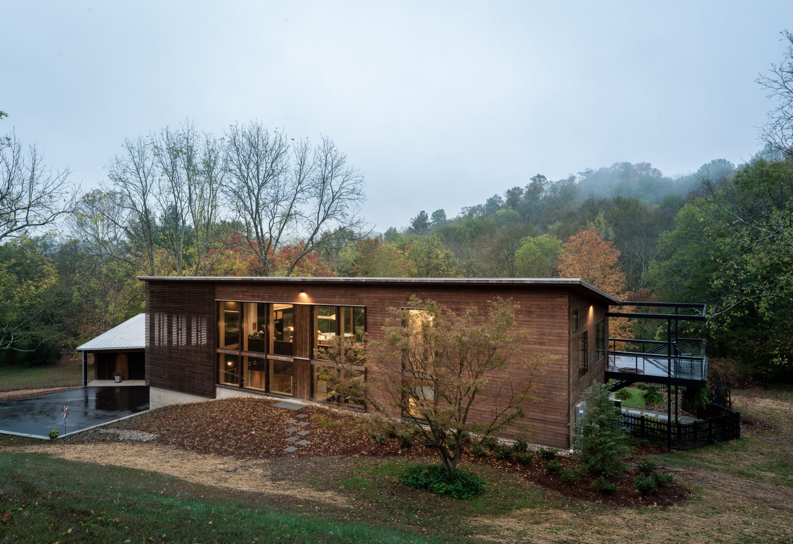 Exterior view of the front entrance with surrounding woods of the Wood Screen House in Nashville, Tennessee during a foggy day featuring Kebony Modified Wood Clear Cladding