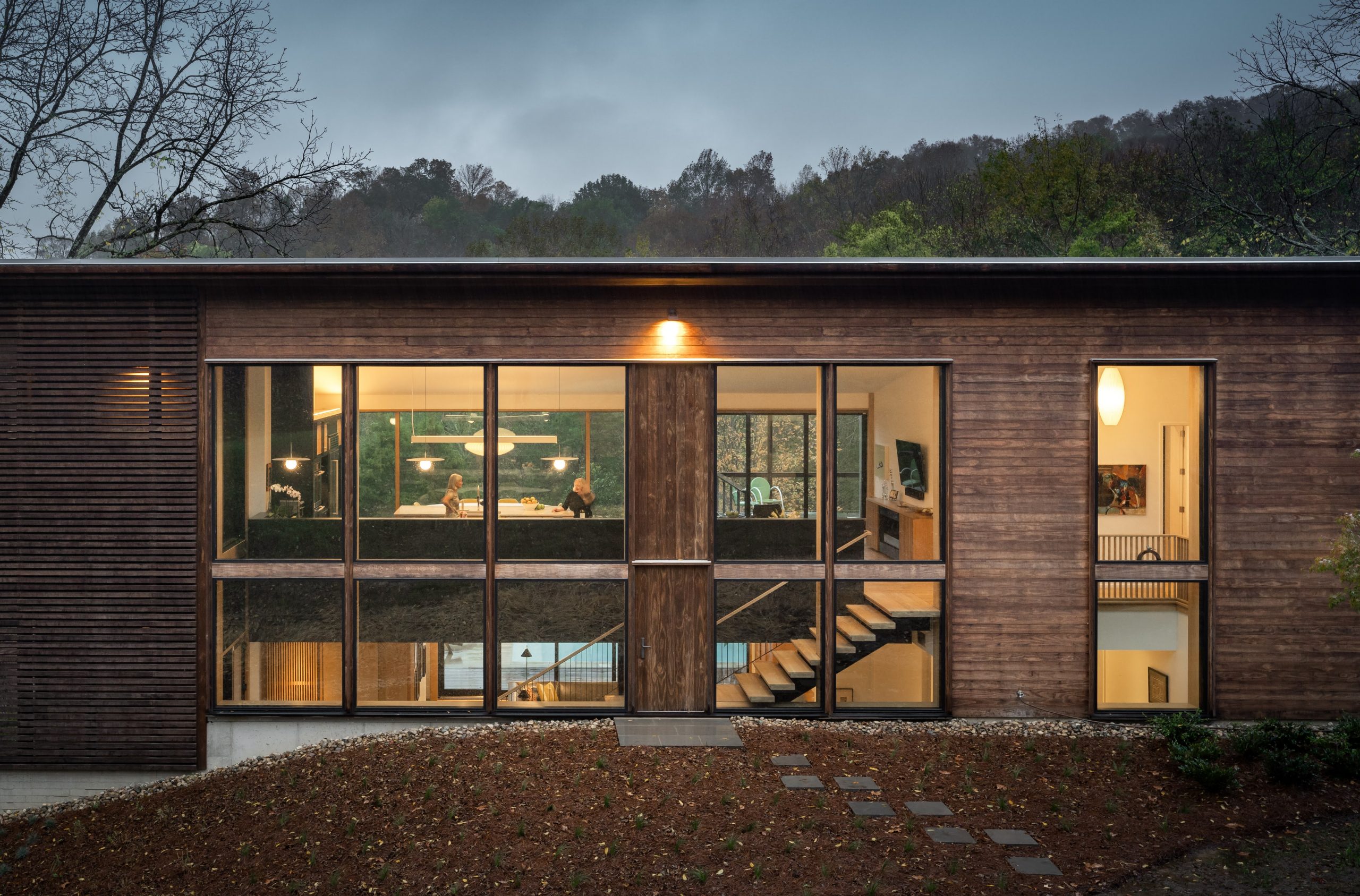 Exterior view of the outside of Wood Screen House in Nashville, Tennessee at nighttime with the interior lights on featuring Kebony Modified Wood Clear Cladding on the siding