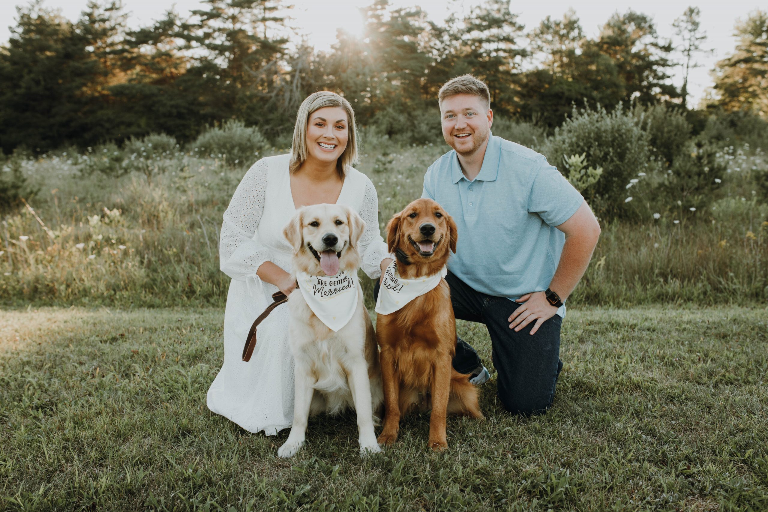 Portrait during a sunset of Kelsey Thibert with her Husband and two dogs in a field