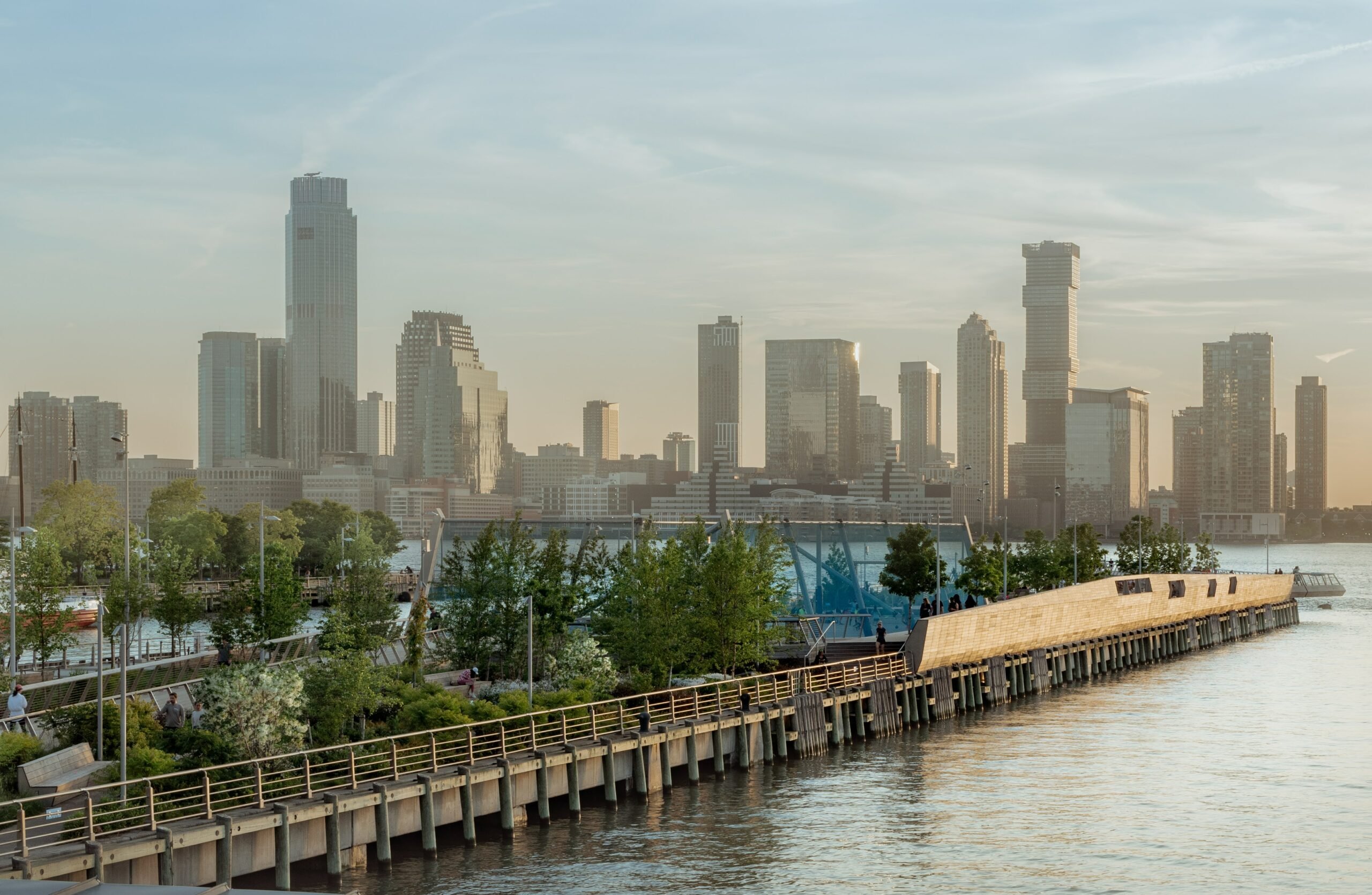 Arial side view looking at The Tide Deck at Pier 26 featuring kebony modified wood Clear Boardwalk Decking during a sunset with the city skyline in the background at Hudson River Park in New York City New York Downtown New York City