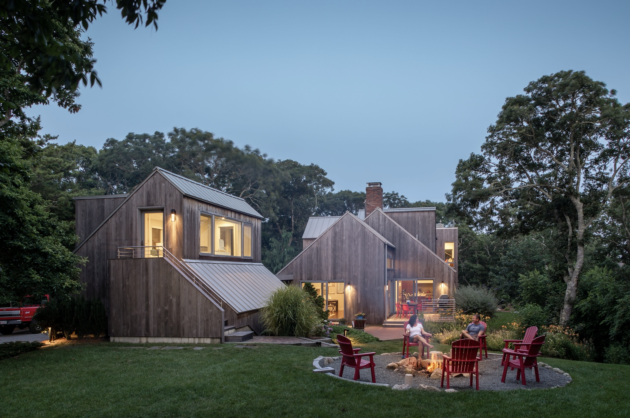 Morris Island Residence couple enjoying their backyard firepit on a beautiful evening on Morris Island in Chatham, Massachusetts featuring Kebony Modified Wood Clear Cladding