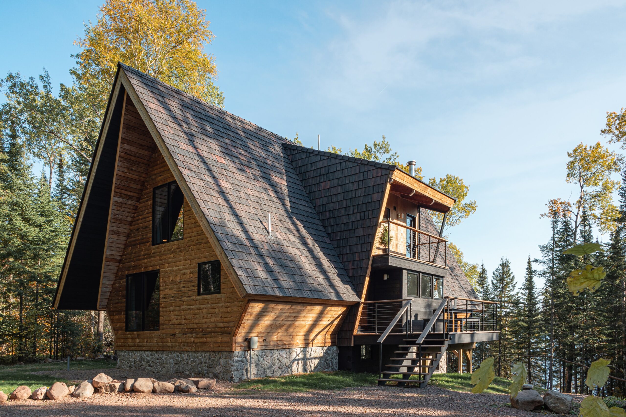 Outside three quarters' view of The Minne Stuga Cabin with patio decking in Grand Marais Minnesota prominently featuring Kebony modified wood siding throughout the houses' design