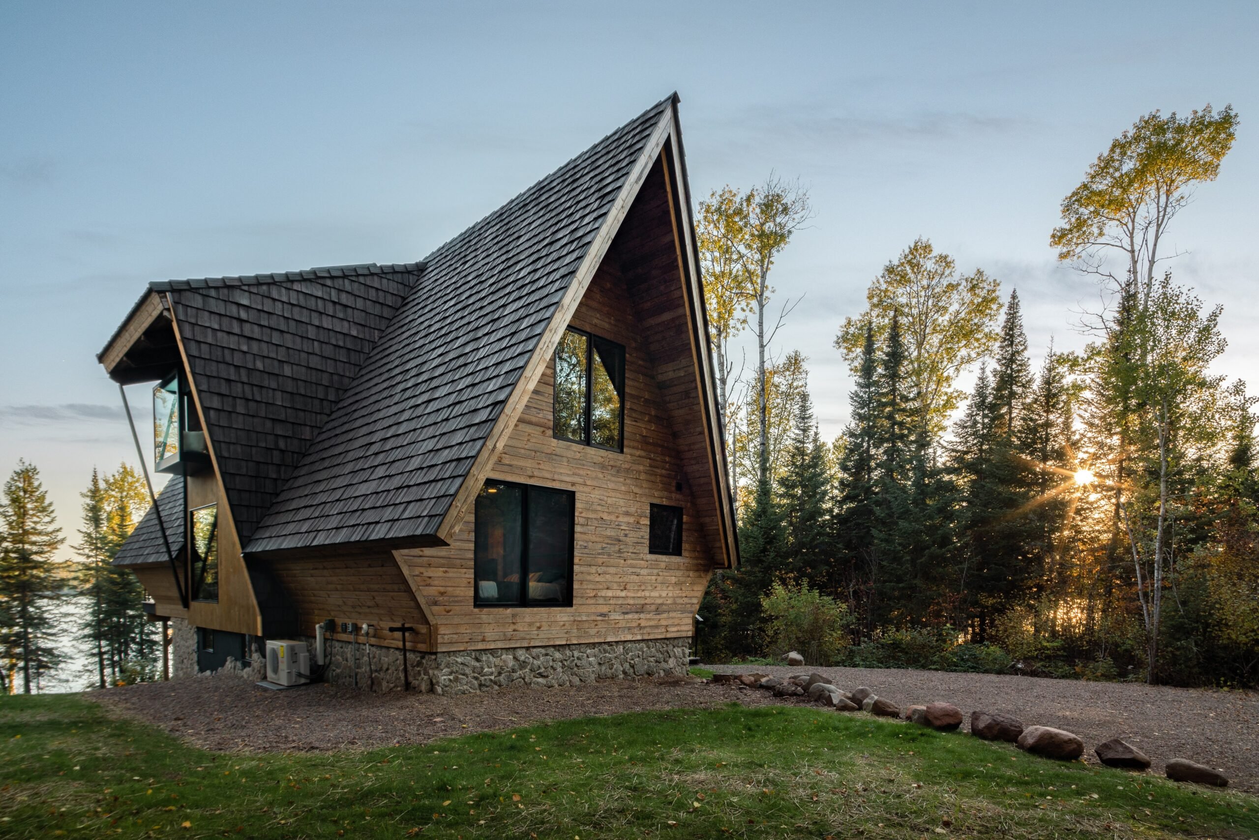 Outside three quarters' view of The Minne Stuga Cabin in Grand Marais Minnesota prominently featuring Kebony modified wood siding at sunset