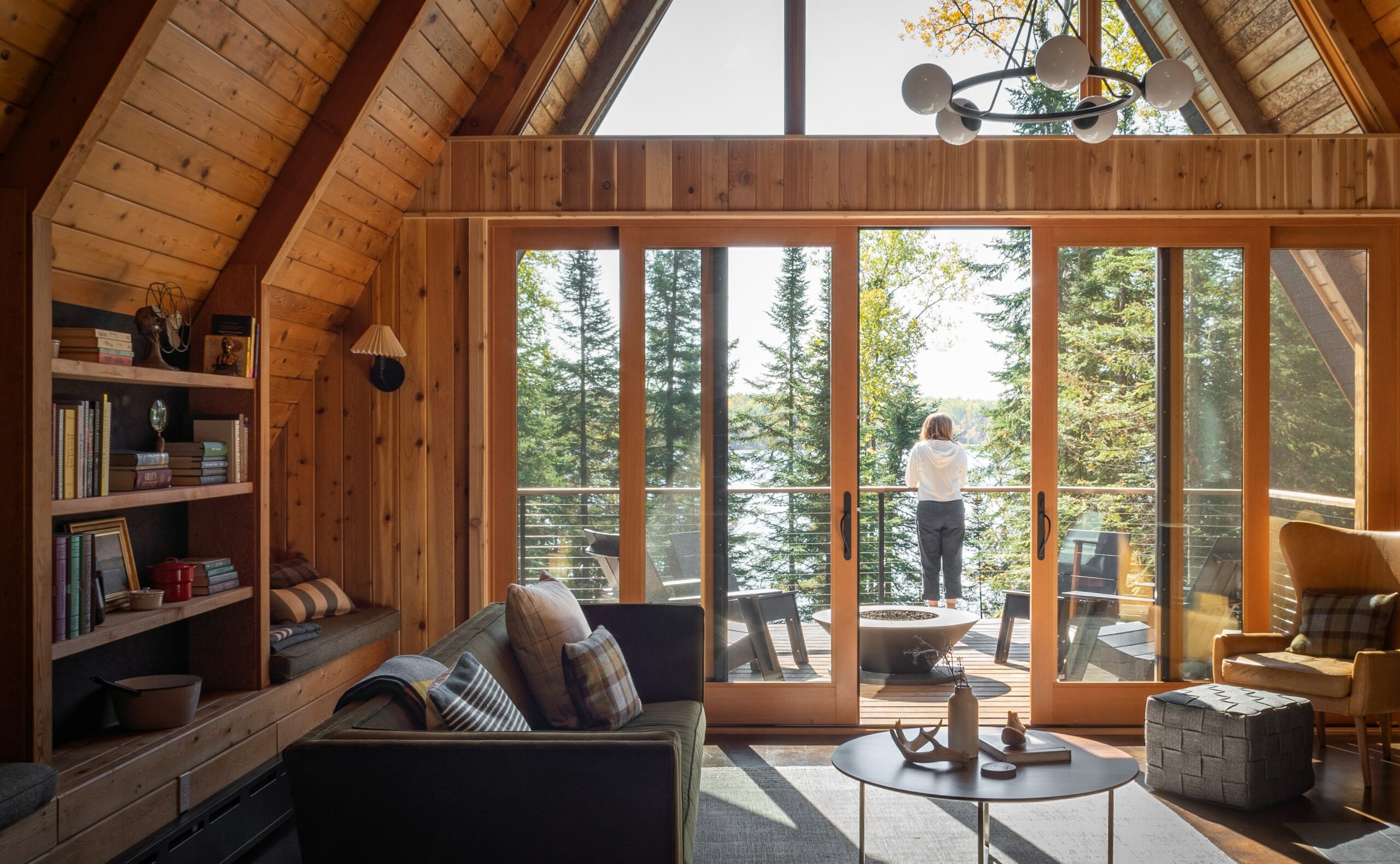 View of the wooded backyard from a living room of The Minne Stuga Cabin in Grand Marais Minnesota prominently featuring Kebony modified wood siding throughout the houses' design
